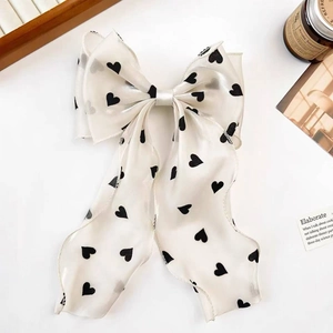 Detail of cream bow hair clip with black heart pattern on elegant ribbon streamer