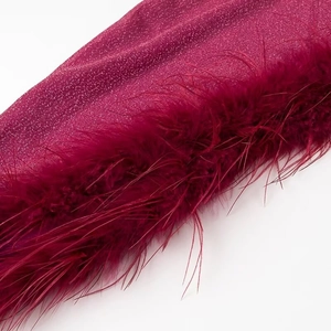 Macro shot of shimmering burgundy glitter fabric and luxurious feather hem detailing