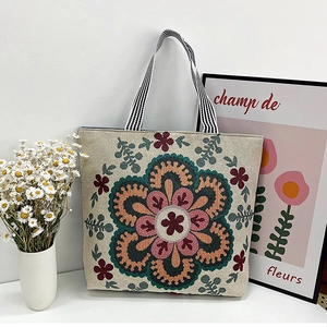 Detail of bohemian floral embroidery on canvas tote bag with striped shoulder strap