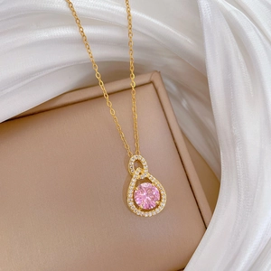Macro detail of gold necklace with pink teardrop crystal and surrounding small diamonds