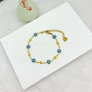Elegant 18k gold plated daisy and star charm bracelet on a textured marble background