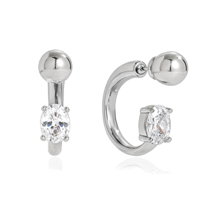 Macro view of C-shaped earrings with oval zircon stone and polished metal sphere