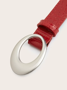 Detail of red faux crocodile leather belt with an oval silver metal buckle