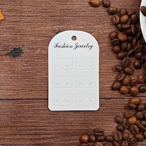 Detailed view of white earring display cards with 12 holes on rustic wood background