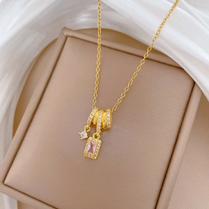 Detailed close-up of a gold necklace featuring a pink rectangular crystal and diamond pavé