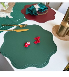 Detail of scalloped edge faux leather placemats in festive green and burgundy red