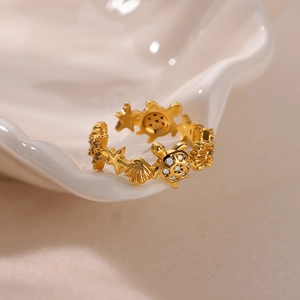 Macro shot of gold starfish and turtle ring with inset crystals on ceramic tray