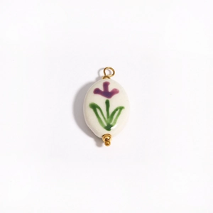 Detailed view of an oval white ceramic pendant with hand-painted purple flowers and 18K gold