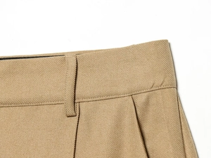 Detailed macro view of khaki twill trousers showing waistband loops and reinforced stitching