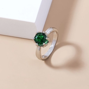 Close-up of a silver ring with a round green faceted gemstone in a six-prong setting