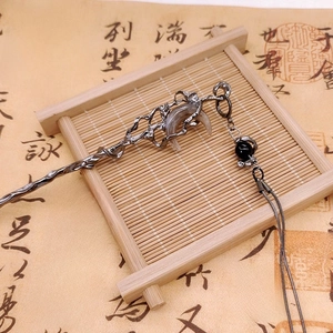 Macro shot of silver metal hair pin with crescent moon and black bead tassels on bamboo mat