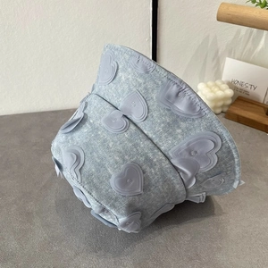 Detailed view of light blue denim bucket hat with decorative 3D heart-shaped patches