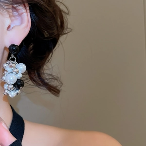 Close-up of beaded tassel earrings featuring black, silver, and pearls on a model