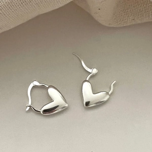 Detailed view of S925 sterling silver heart-shaped hoop earrings on neutral background