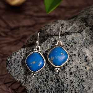 Macro detail of geometric lapis lazuli earrings with vintage silver frames and beads