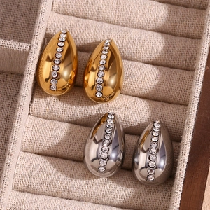 Macro shot of 18K gold and silver water drop earrings with rhinestones in a box