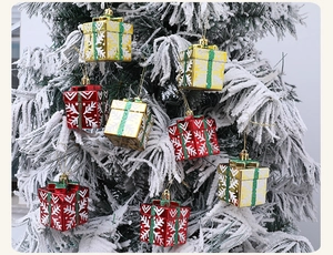 Detail of red and gold mini gift box ornaments with snowflake patterns on snow-covered trees