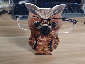Detailed close-up of a wooden owl-shaped glasses stand showing realistic feather textures