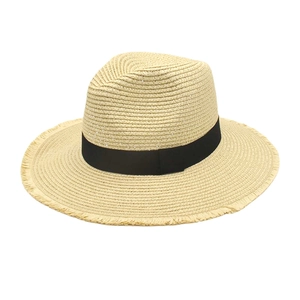 Détail d'un chapeau de soleil en raphia avec ruban noir et bord à franges stylé