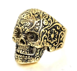 Close-up of golden sugar skull ring featuring intricate floral carvings and metal textures