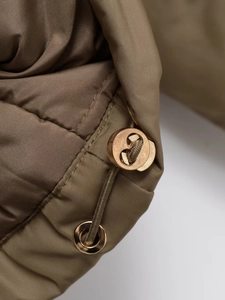 Dettaglio del coulisse regolabile con occhielli metallici sul parka kaki