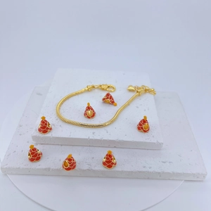 Close-up of golden snake chain bracelet with red and gold cone-shaped enamel charms