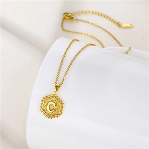 Minimalist gold stainless steel necklace featuring a hexagonal letter C pendant on a white base