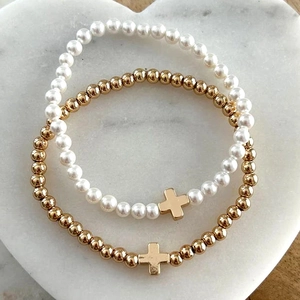 Detail of beaded cross bracelets with pearls and gold beads on a marble tray