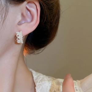 Close-up of French vintage crown pearl earrings with lace metal details and small diamonds