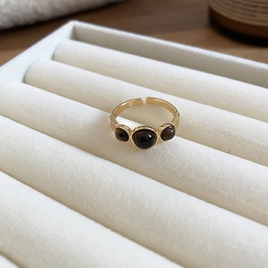 Detailed macro view of 18k gold-plated ring set with three polished brown tiger eye stones