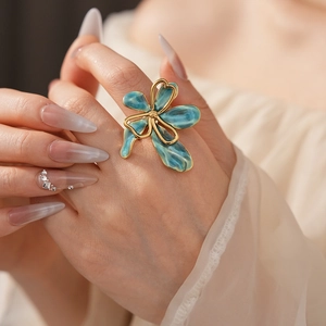 Macro shot of a vintage-style blue enamel flower ring worn on the finger with gold detailing