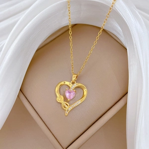 Detail of gold heart pendant with pink gemstone and sparkling pavé on silk background