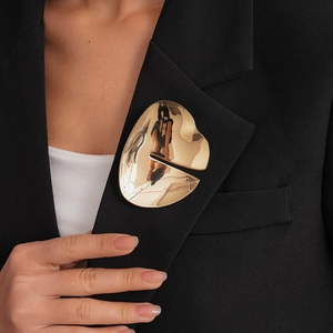 Detailed view of an irregular organic golden brooch worn on a black suit lapel