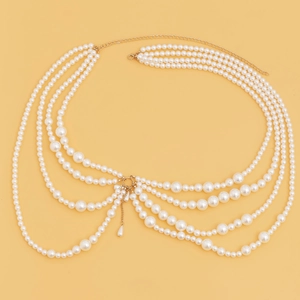 Detail of layered gold waist chain featuring white pearls and elegant drop pendant