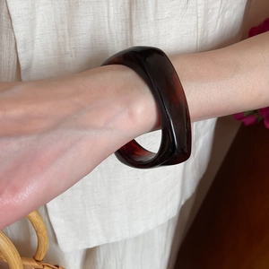 Close-up of wide tortoiseshell resin bangle on wrist with vintage brownish-black texture