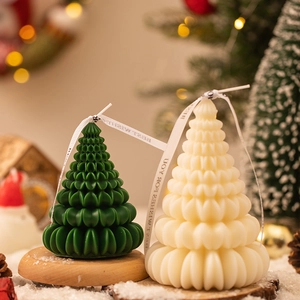 Christmas tree shaped scented candles in green and cream white on a wooden base