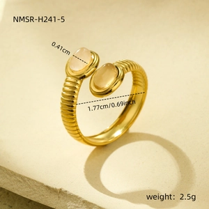 Macro detail of gold-plated striped ring featuring oval cat-eye stones on a stone base