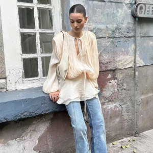 Bohemian beige pleated top with puff sleeves and ruffled hem on a model outdoors