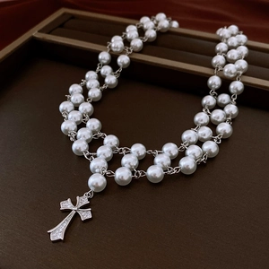 Close-up of double-layer pearl necklace with a gothic zircon cross pendant on silk