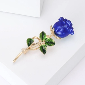 Detail view of elegant blue rose brooch with green leaves and golden metal stem