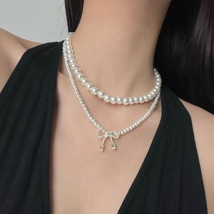 Detail of double-layer pearl necklace with a sparkling bow pendant and zircon drops