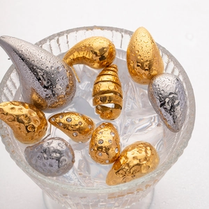 Close-up of 18K gold and silver waterdrop earrings with water droplets in an ice glass
