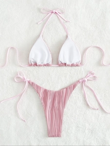 Dettaglio del set bikini rosa a pieghe su sfondo di morbida pelliccia bianca