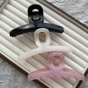 Three large jelly-colored hair claws in black, white, and pink on a velvet jewelry tray