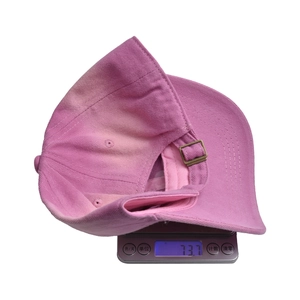 Pink cotton kids baseball cap weighing 73.7g on a digital scale for size reference