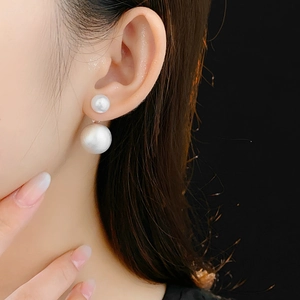 Close-up of brushed metal and pearl double-sided stud earring worn on model ear