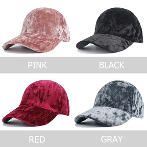 Detail view of velvet baseball caps in pink, black, red, and gray with plush texture