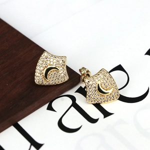 Gold shield-shaped stud earrings featuring a crescent moon and micro-set cubic zirconia