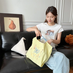 Détail du tote bag brodé jaune en oxford avec motifs de papillons bleus et étoiles