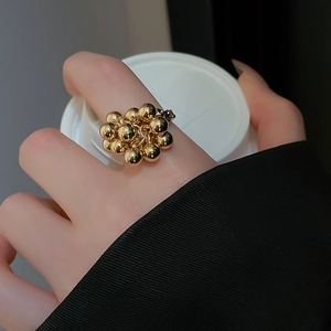 Detailed view of irregular gold cluster bead ring worn on finger with glossy finish